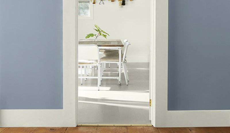 Blue hallway, white trim, sunny white dining room, wood ceiling, white furniture, wood table.