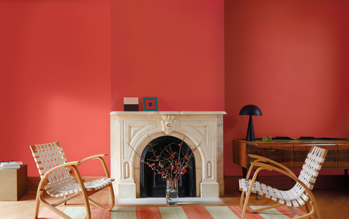 Sala de estar con paredes pintadas de color rojo Raspberry Blush, chimenea de mármol blanco.